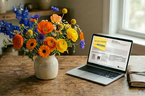 A desk with flowers and laptop displaying a 2026 annual benefit statement.